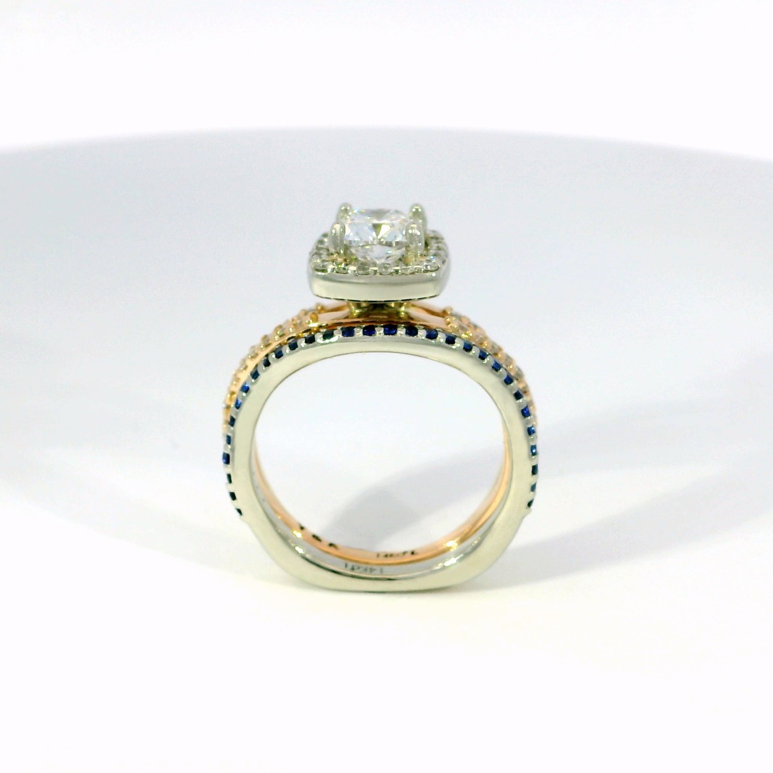 Anillo terminado en oro blanco y rosado con halo de diamantes y zafiros